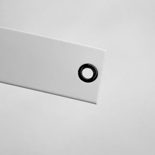 Close-up of a white panel with a black eye rivet on a light gray background