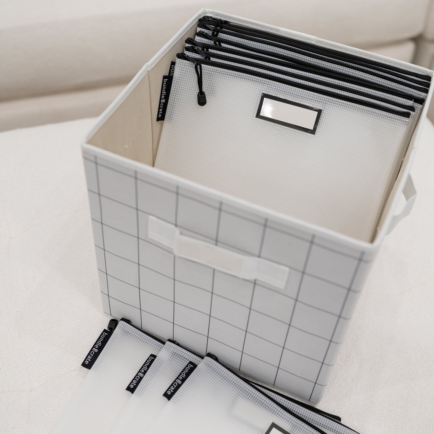 Windowpane grid pattern storage box cube bin with black file folder zipper pouches on a light surface